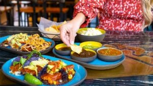 A woman eats three different types of Mexican food with three different sauces.